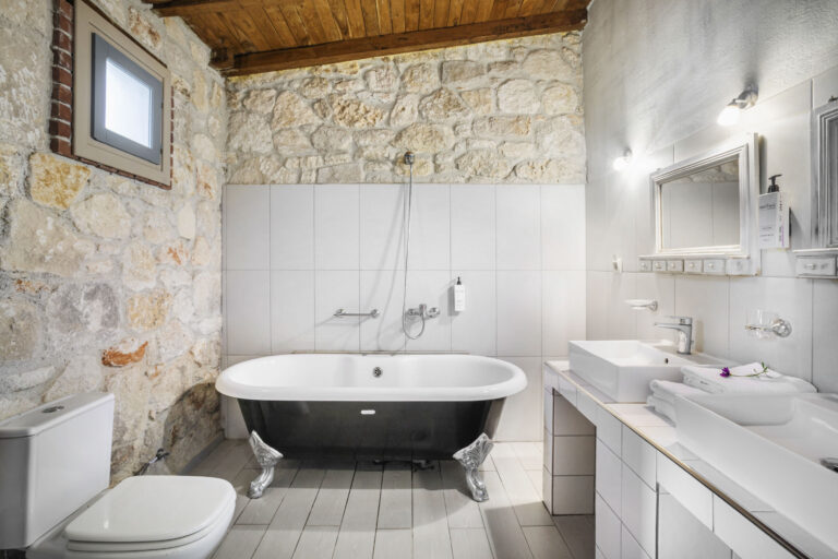 Junior Suite bathroom with freestanding bathtub and stone wall.