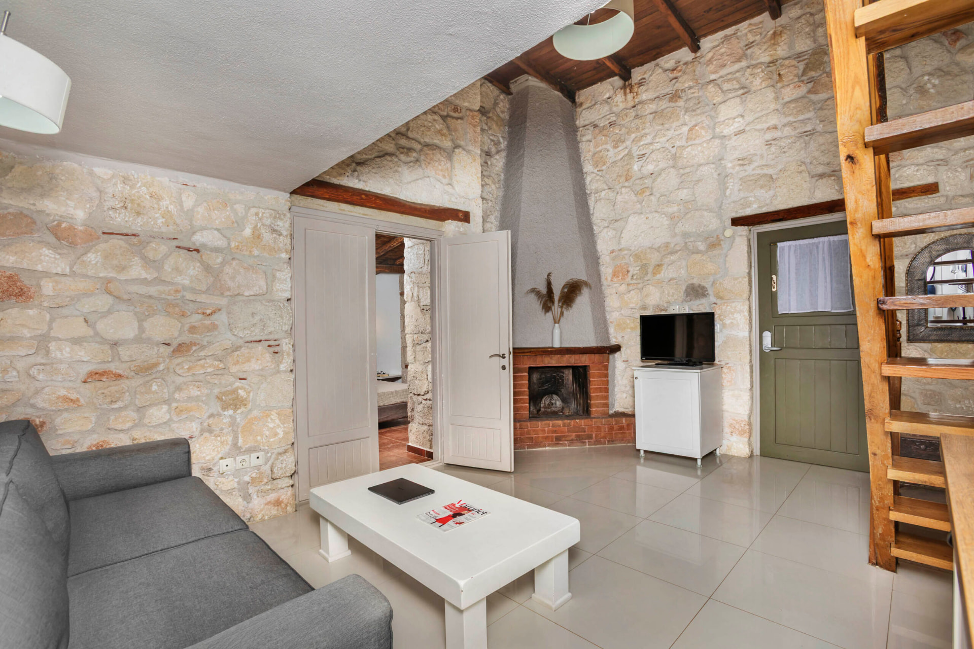 Living room with fireplace, sofa and wooden stair to the loft.