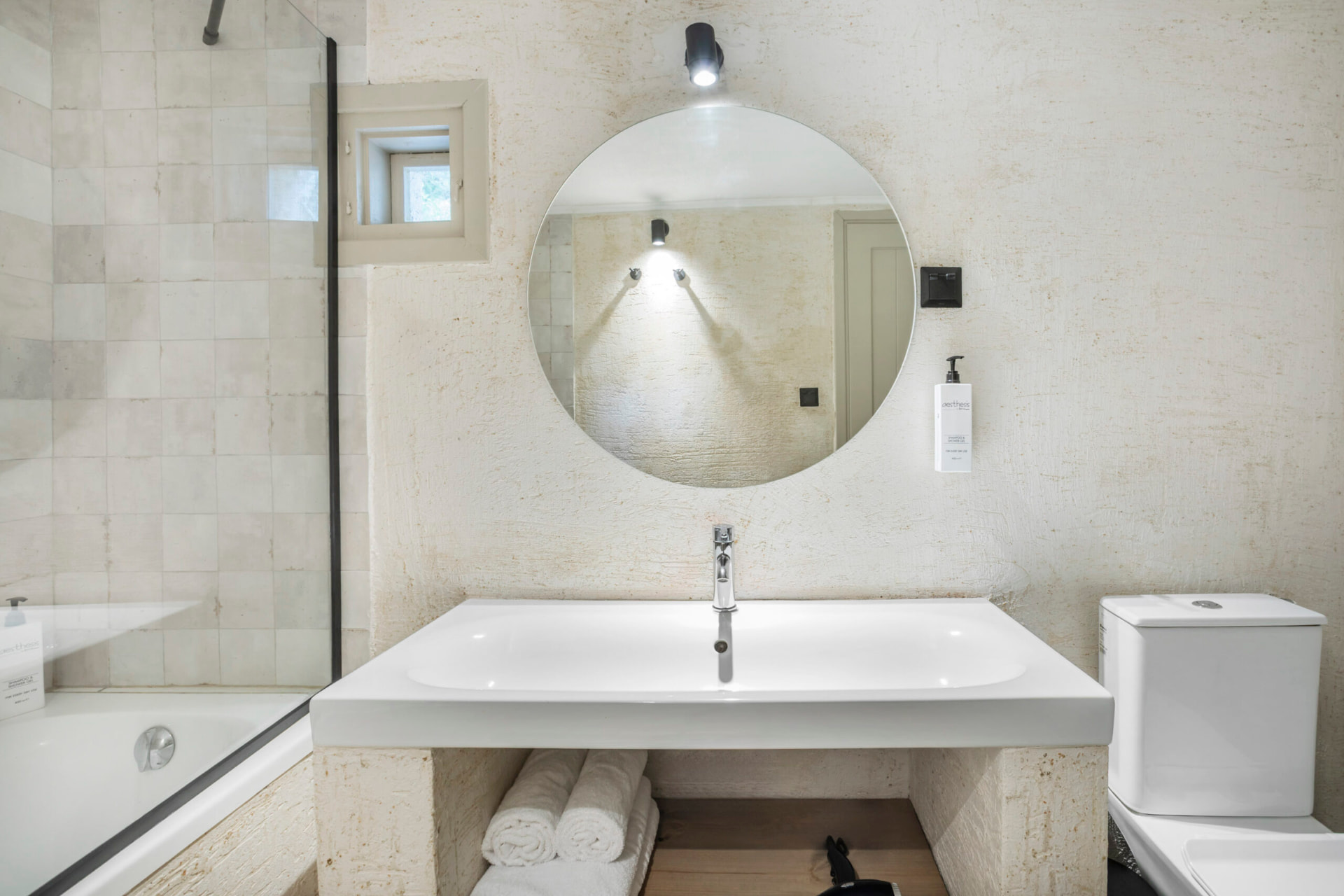 Bathroom with round mirror and bathtub.