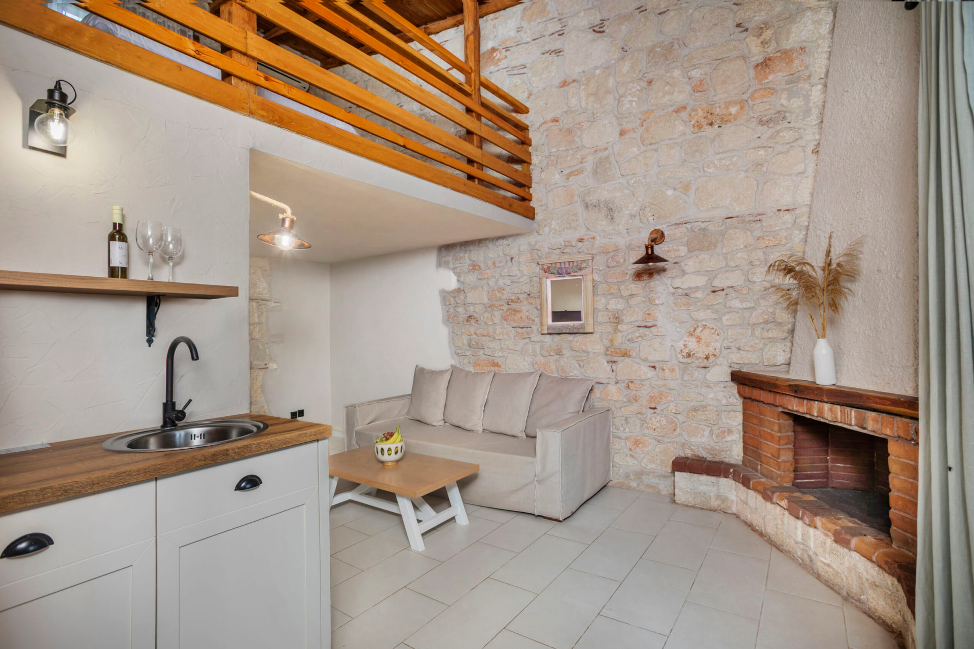 Living area with kitchenette, fireplace and loft above.