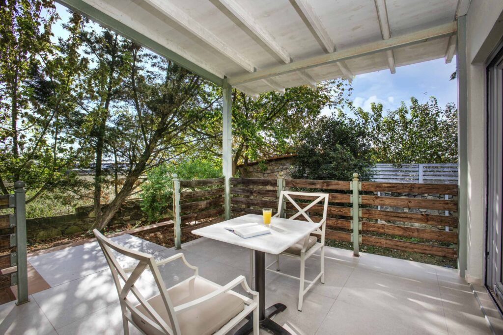 Private shaded veranda with table for two overlooking the greenery.