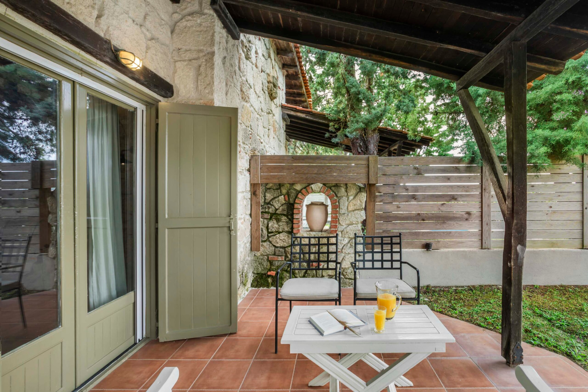 Shaded private veranda with table and garden access.